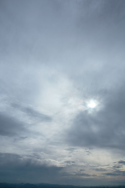 厚い雲間から漏れる日差し、雲空のグラデーション。山際からわき上がる雲、ダイナミックな表情。雲の写真2点。縦の画像。無料写真素材