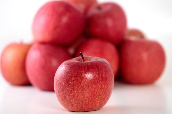 手前に配置した一個の林檎にピントを合わせ、背後に真っ赤に熟した林檎を数個積み重ねて背景にした。新鮮な林檎